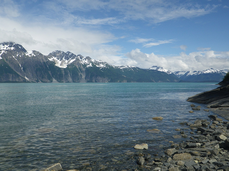 Rugged mountains line a blue-green body of water.