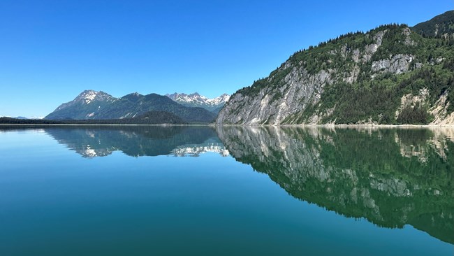 Mountains in Glacier Bay reflect in calm water.