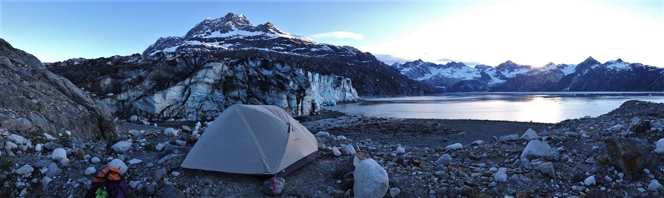a tent near a tidewater glacier and mountains