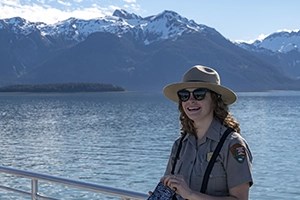 Park Ranger smiles with coastal mountain scenery behind her.
