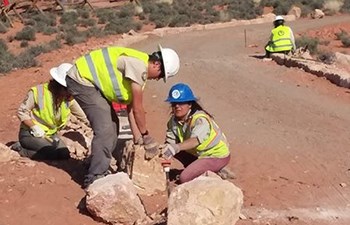 Young people in hard hats position rocks at trail edge