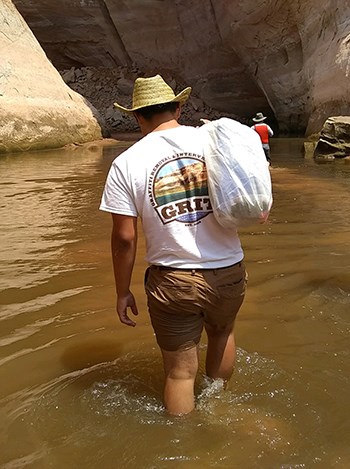 What to Bring Man in GRIT tshirt heaves bag over shoulder as he walks through shallow water