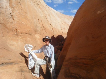 Person in a hat holding a trash bag in one hand, grabbers in the other, smiling.