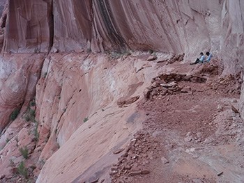 Two people sitting in large sandstone alcove