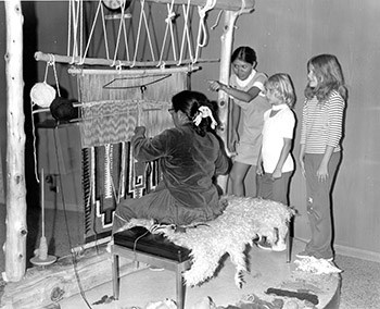 Navajo weaver at loom, Park Ranger points out loom to children