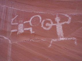 Two ancient figures are painted on the cliff wall. they hold shields and appear to be fighting.