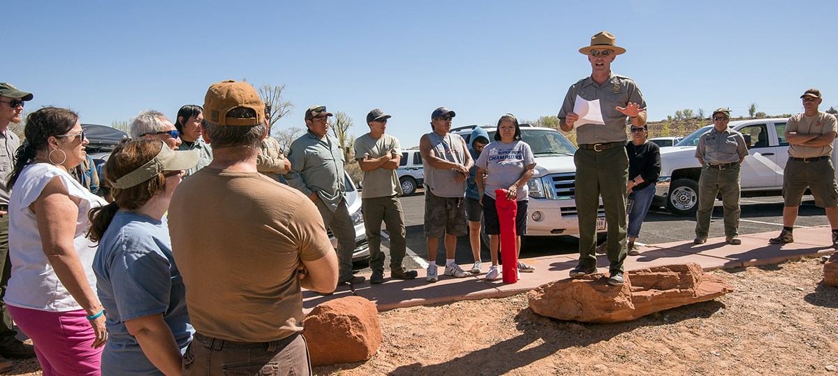 Superintendent stands on a small rock to speak to a gathered crowd