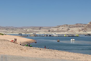 Small group of people and water toys on beach next to large boat dock