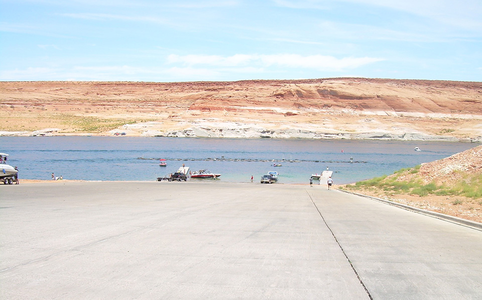 Paved launch ramp leading to lake, boats and cars on the sides and launching