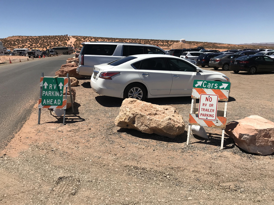 Dirt parking lot full of cars and hazard signs