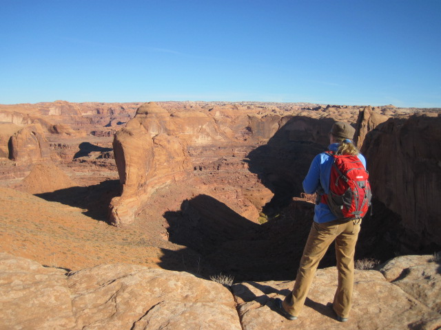 Hiker with backpack stands at edge of cliff