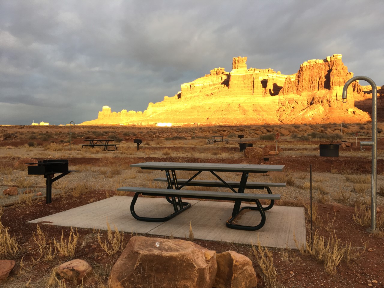 Picnic table on paved slab near a charcoal grill at Hite Developed Campground