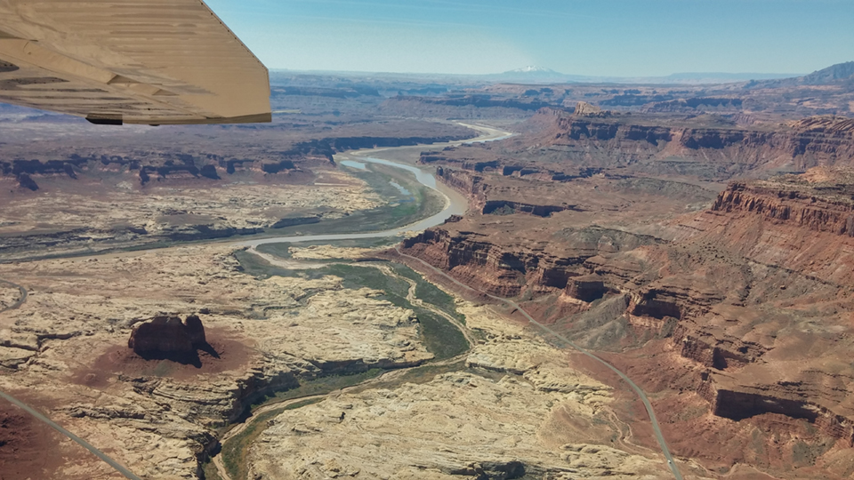 Aerial view of canyon and river with airplane wing in shot