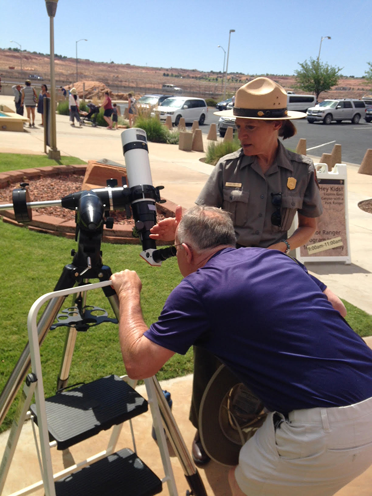 Ranger helps man looking through telescope on sunny day