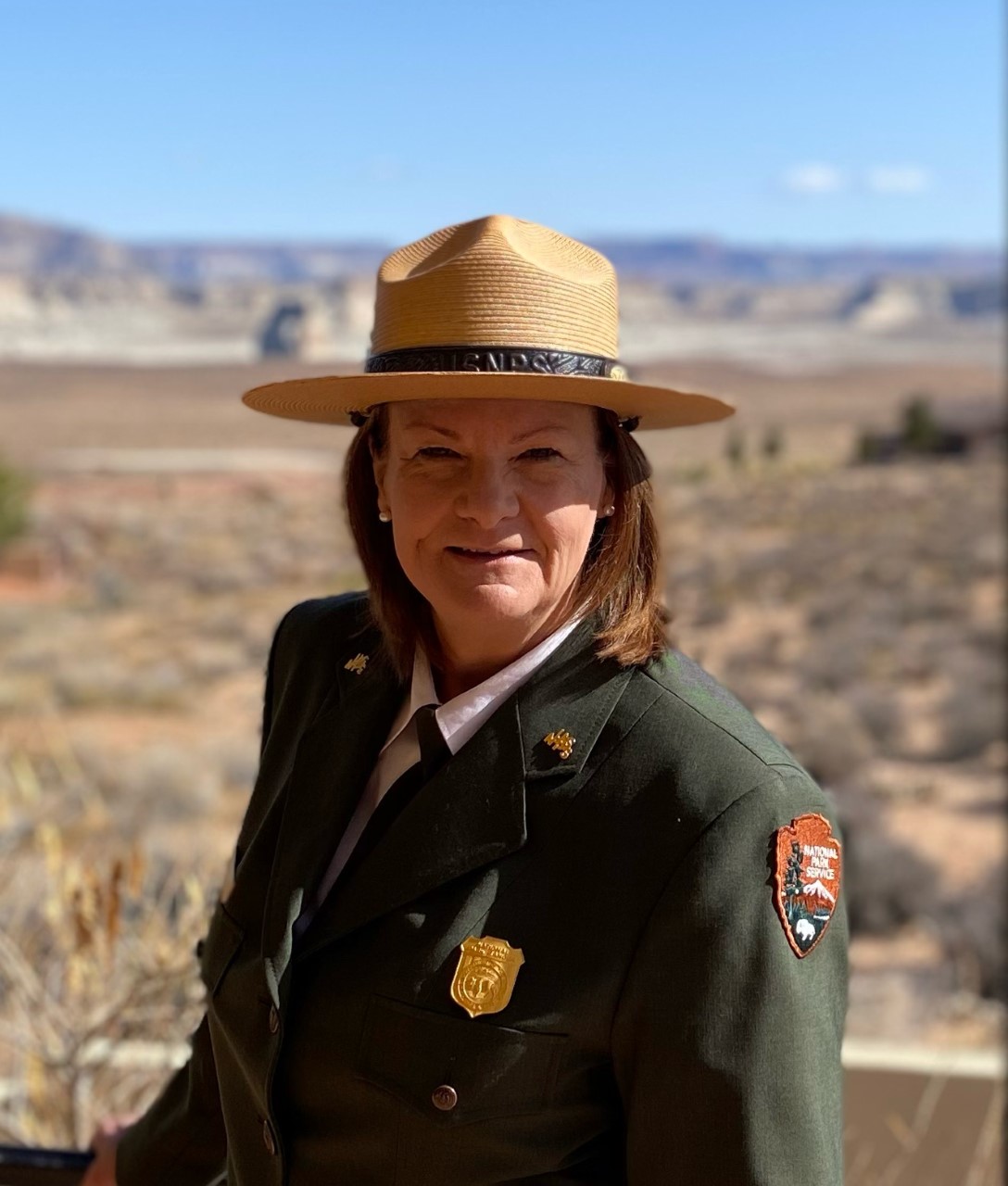 Park ranger in formal uniform outdoors smiling at the camera