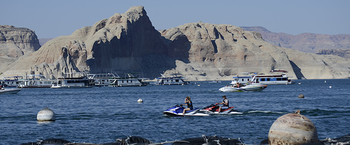 View of lake with boats in foreground, rock cliffs in background