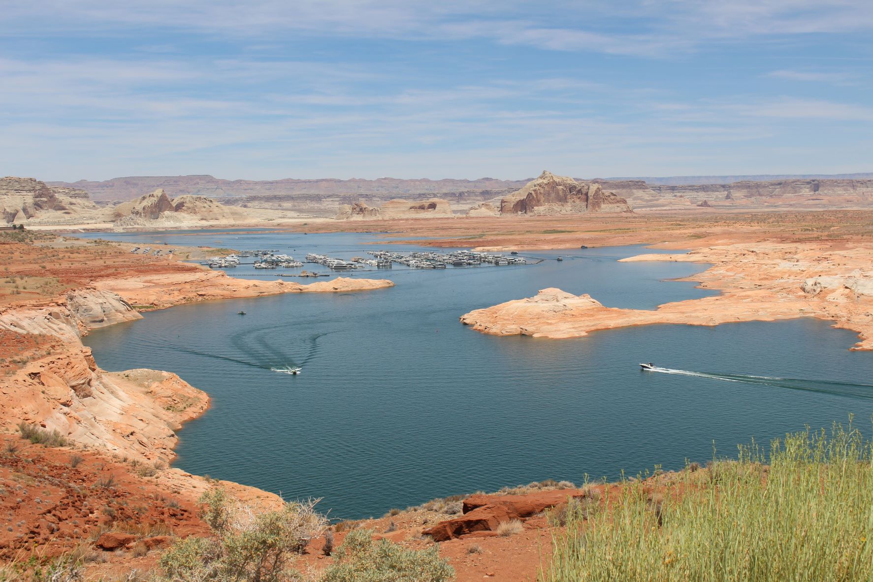 two small boats leave a wake on a winding lake