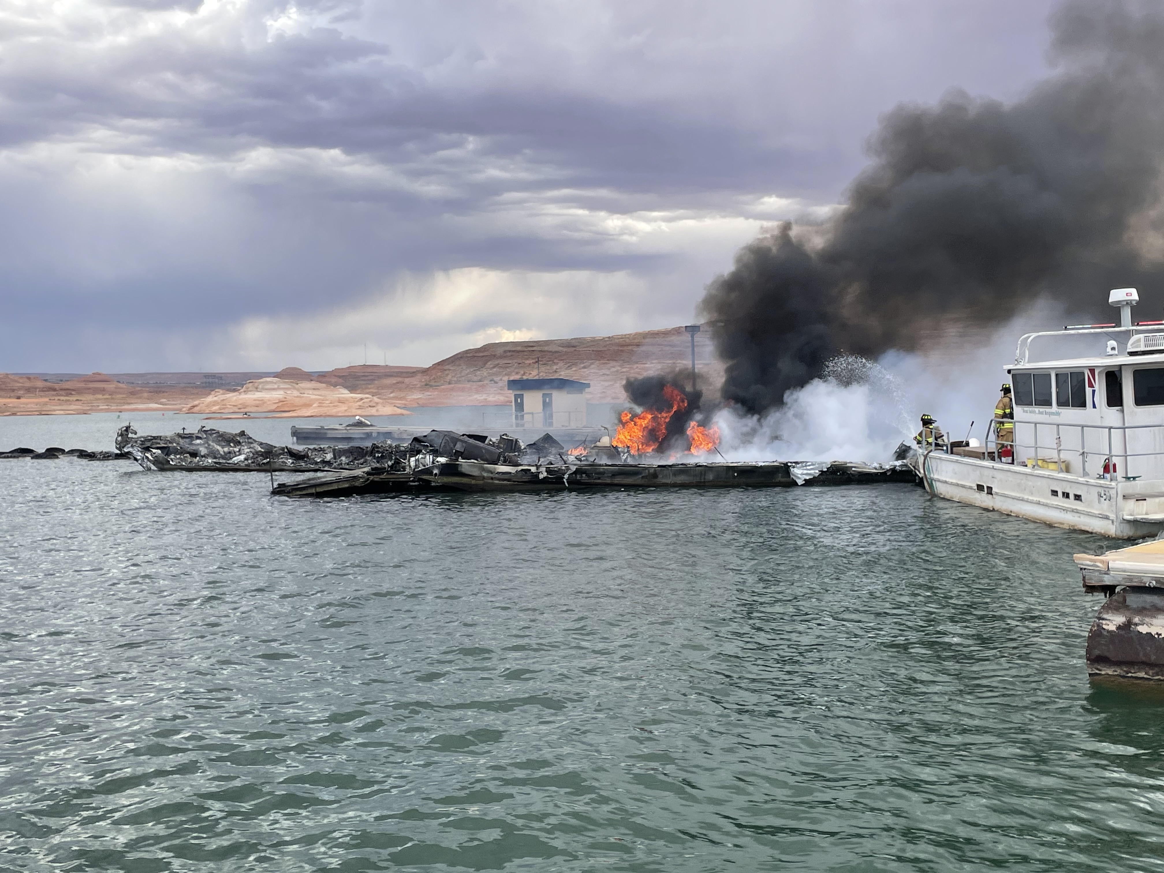 Park Ranger firefighters from a boat spray water on a fire on marina docks