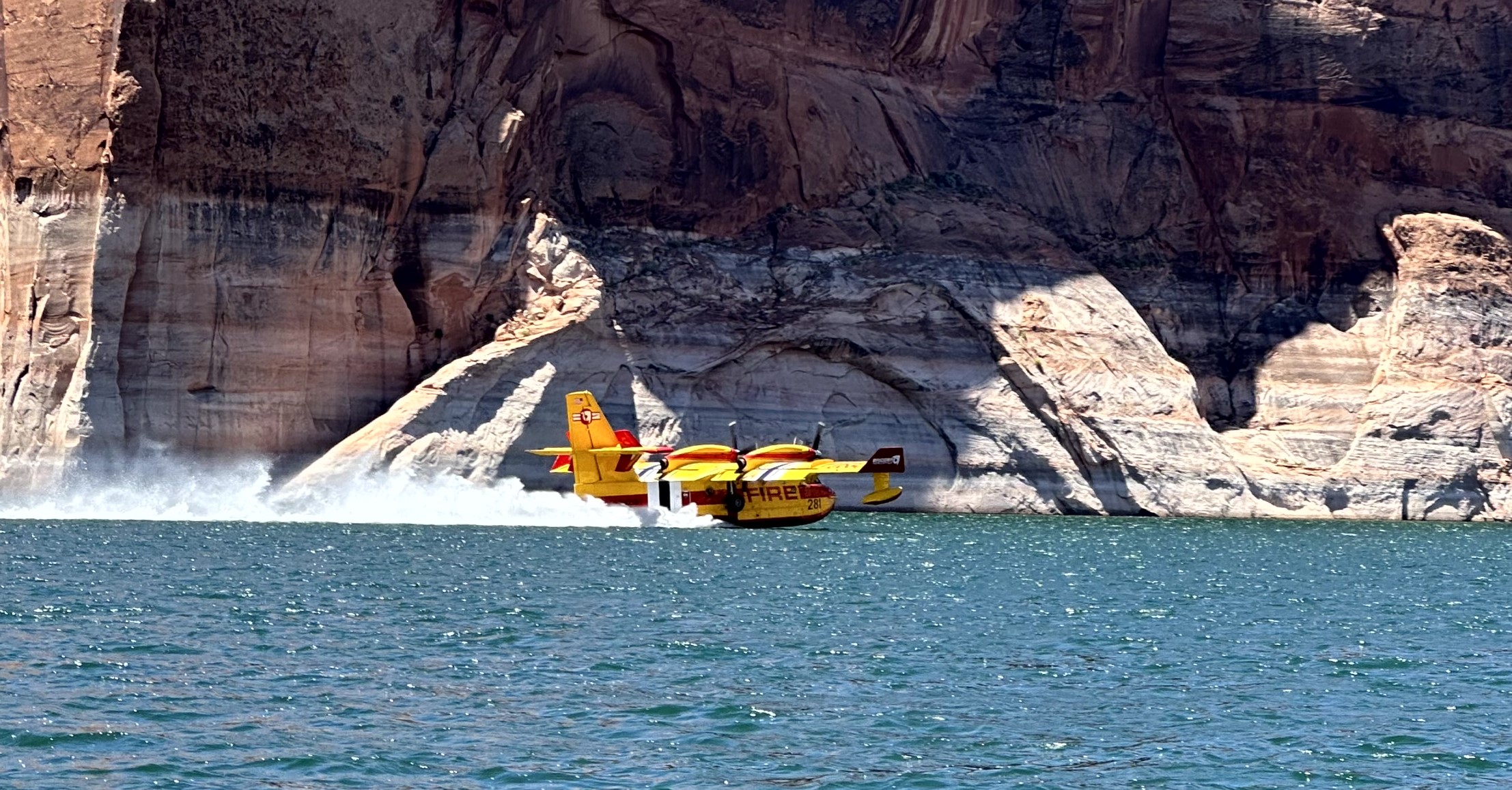 Yellow airplane flies low over a desert lake