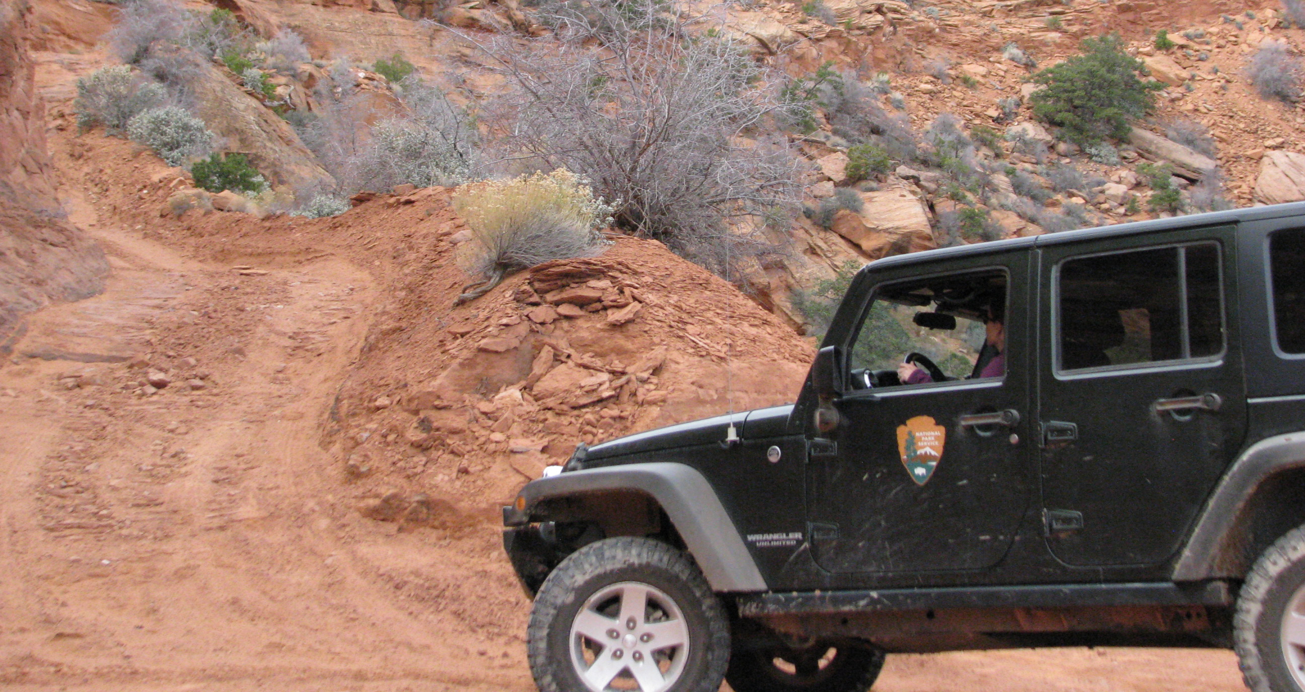 Jeepin in Glen Canyon A jeep drives up a sandy road in a rocky canyon.