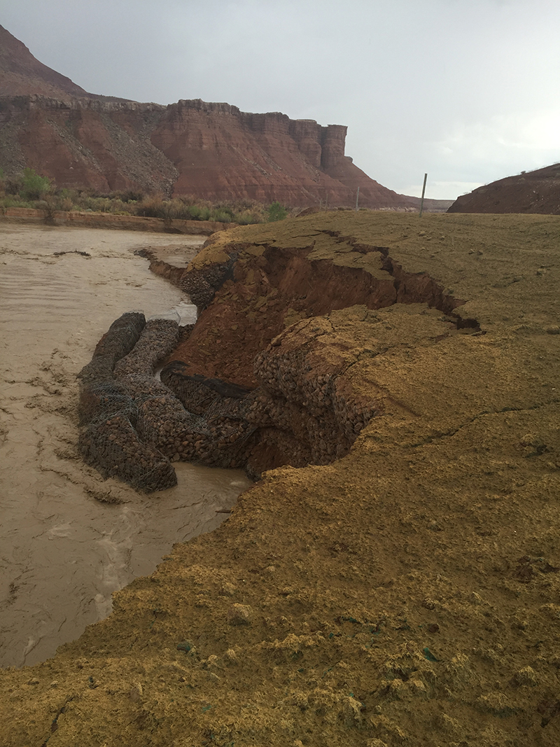 Dark sediment filled river bend with the bank falling into the water.