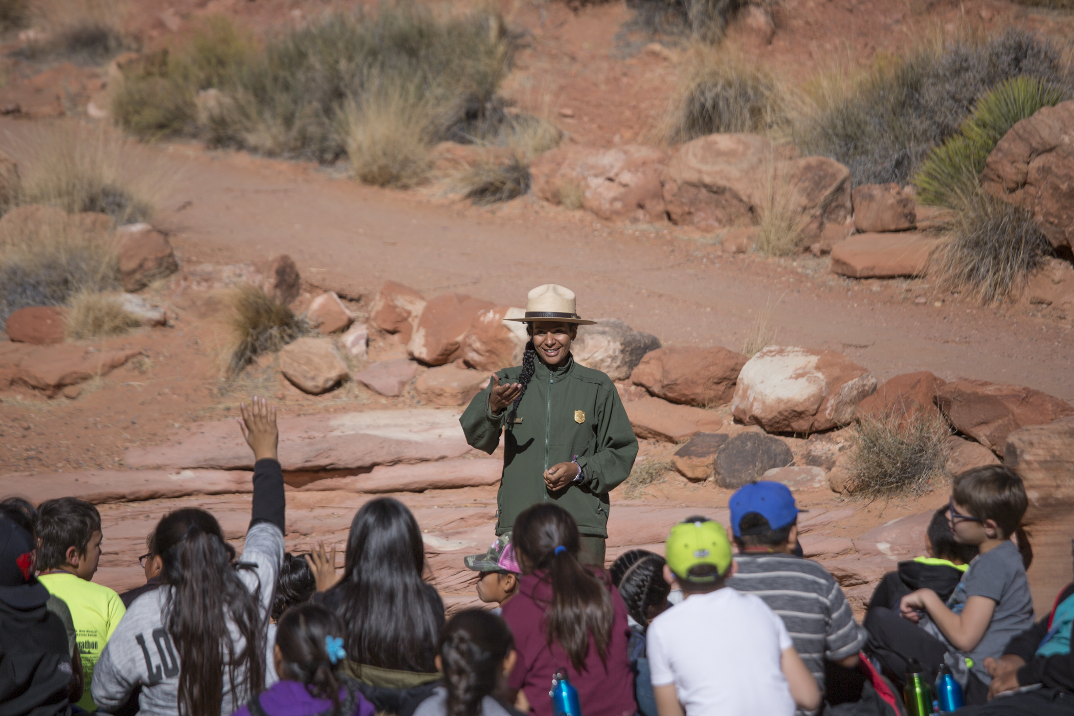 National Park Service Ranger Edmonia Martinez and students from Lake Powell School in Bullfrog, Utah, and Bluff Elementary School in Bluff, Utah, enjoy stories about the history of Rainbow Bridge Park Ranger addresses group of children