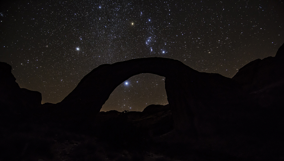 Night view of starry sky behind sandstone arch