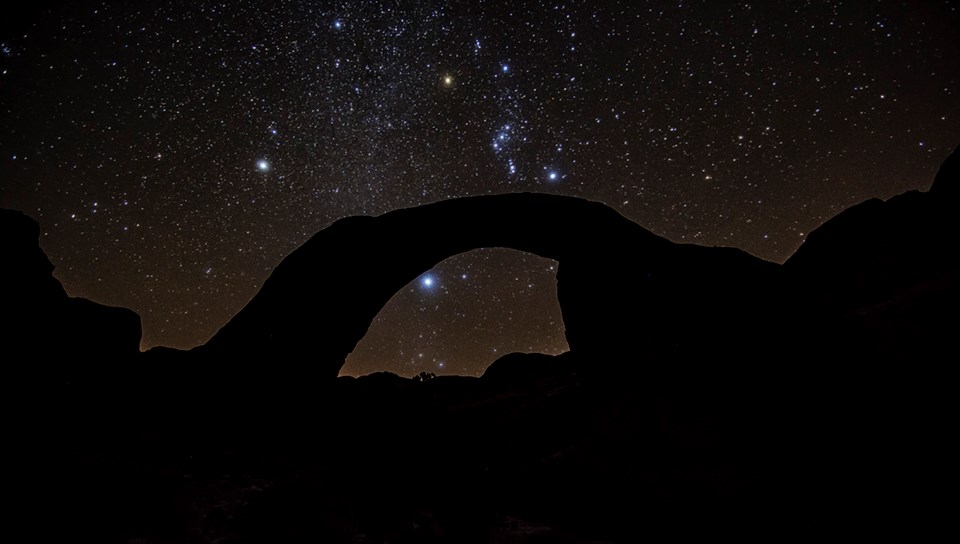 Night view of starry sky behind sandstone arch