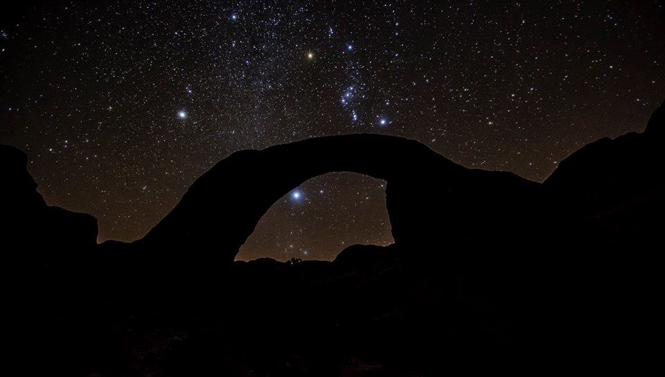 Rainbow Bridge at Night. NPS Photo by Brent and Dawn Davis Night view of starry sky behind sandstone arch