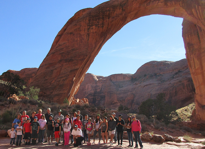 Group of people, mostly children, pose in front of Rainbow Bridge