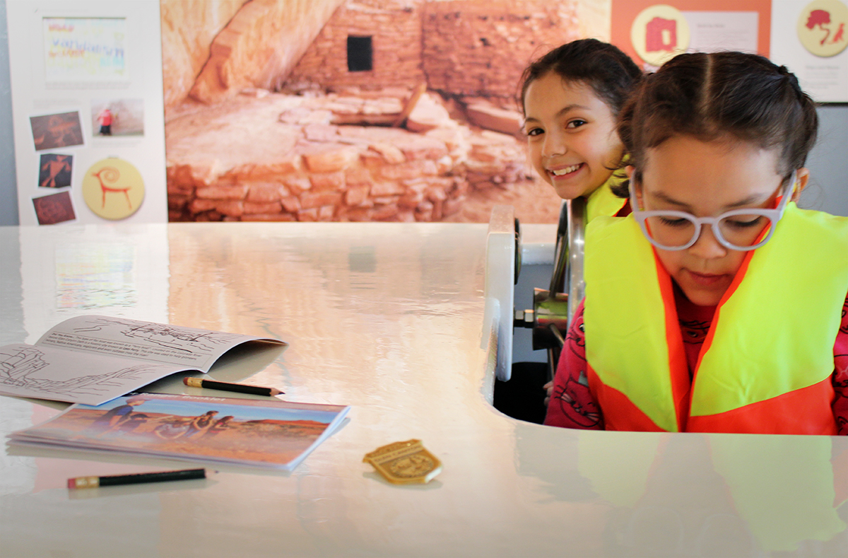 Jr Ranger sisters Two girls wearing life jackets in play boat with exhibit panels in background
