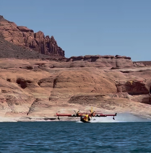 Super Scooper Airplance flying very close to the surface of a desert lake.