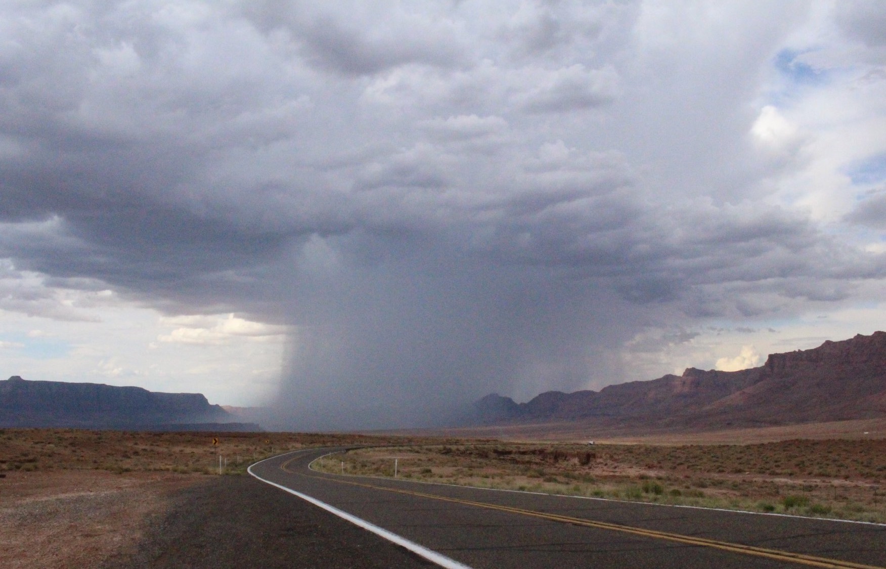 Microburst dark cloud dumps column of rain on landscape