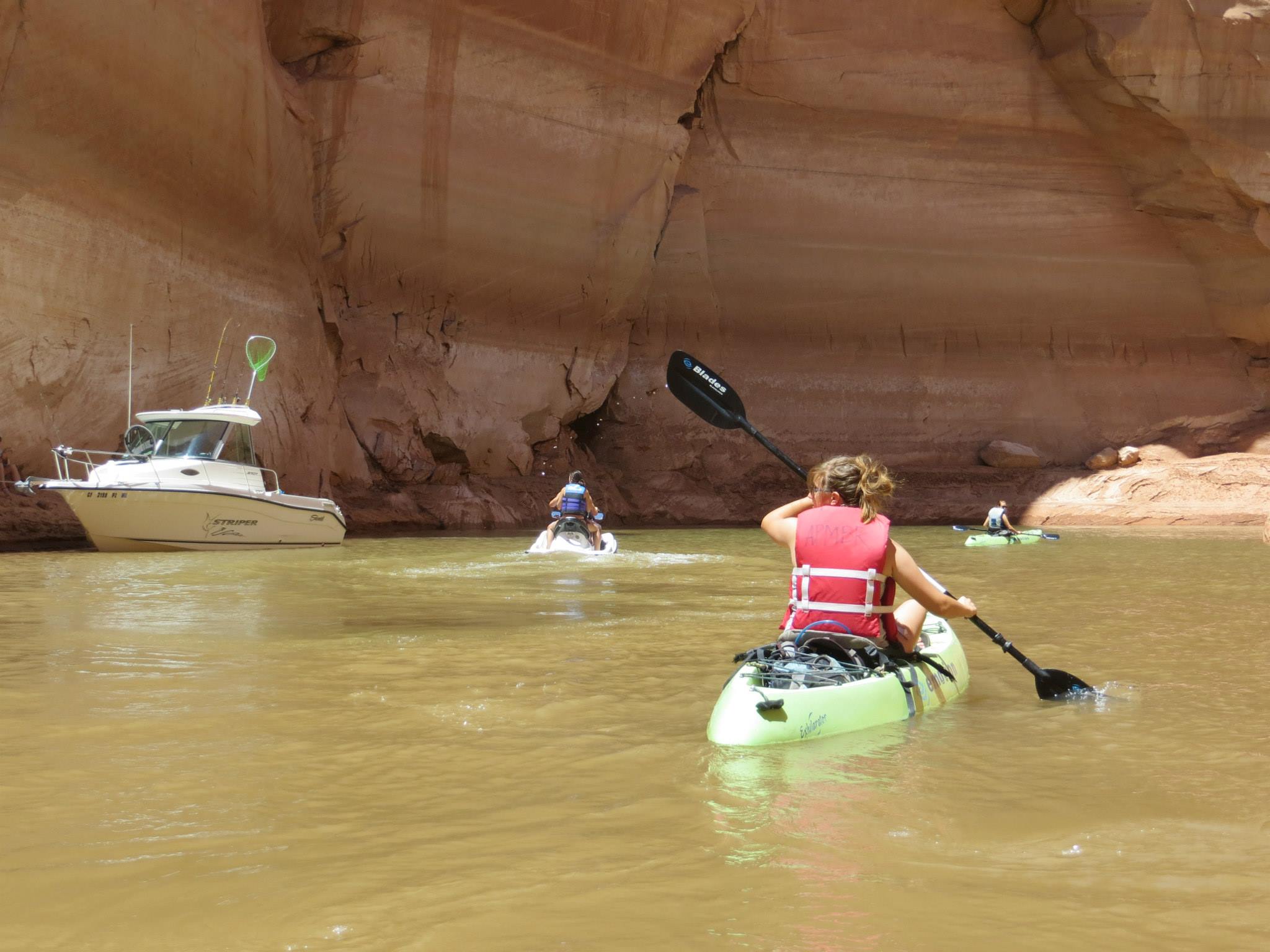 Kayaker, motorboats on a lake in a sandstone canyon