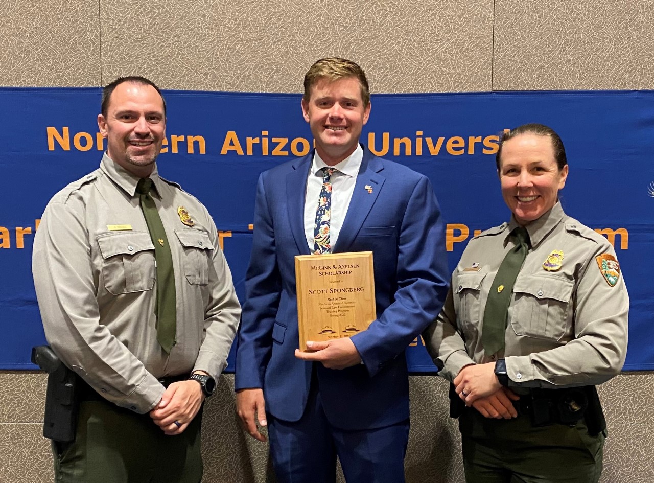 thumbnail_GLCA - Glen Canyon Ranger Scott Spongberg Receives Prestigious Award. NPS Photo L-R, Deputy Chief of Operations Jamey Brazell, Scott Spongberg, Chief Ranger Jessica Barr three people stand next to each other posing for a picture smiling , the middle person holding award plaque
