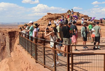 Group of people stand behind a fence looking in the distance.