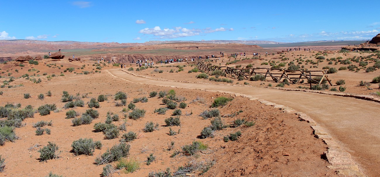 Hard surface trail lined in rocks gently turns toward canyon rim