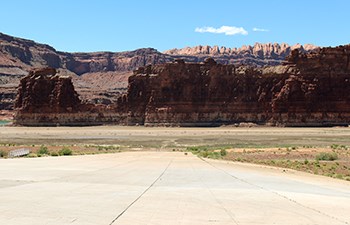 Looking down long paved ramp leading to water below dark cliffs