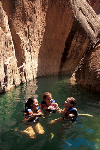 Three women wearing life jackets happily tred water in slot canyon
