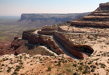 Unpaved road switchbacks through rocky mesa