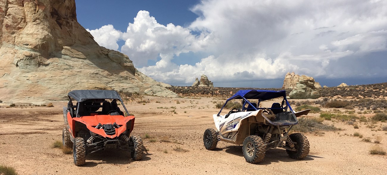 two off-road vehicles on hard sand near a road