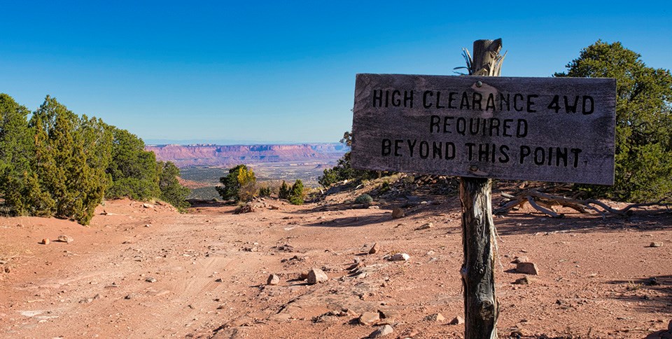 Sandy landscape, wooden sign: High Clearance 4WD Required Beyond This Point