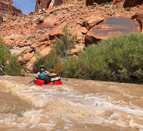 Rafter maneuvers past rock in rapid