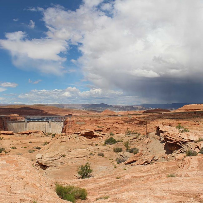 Dark storm clouds and rain loom over the lake with a view of the dam