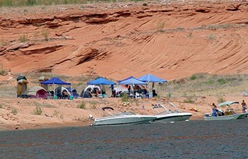 Group of tents and canopies set up near waters edge where boats are anchored