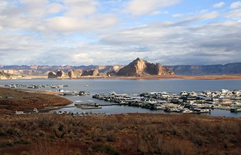 Soft sunlight on cliffs behind busy dock full of moored houseboats