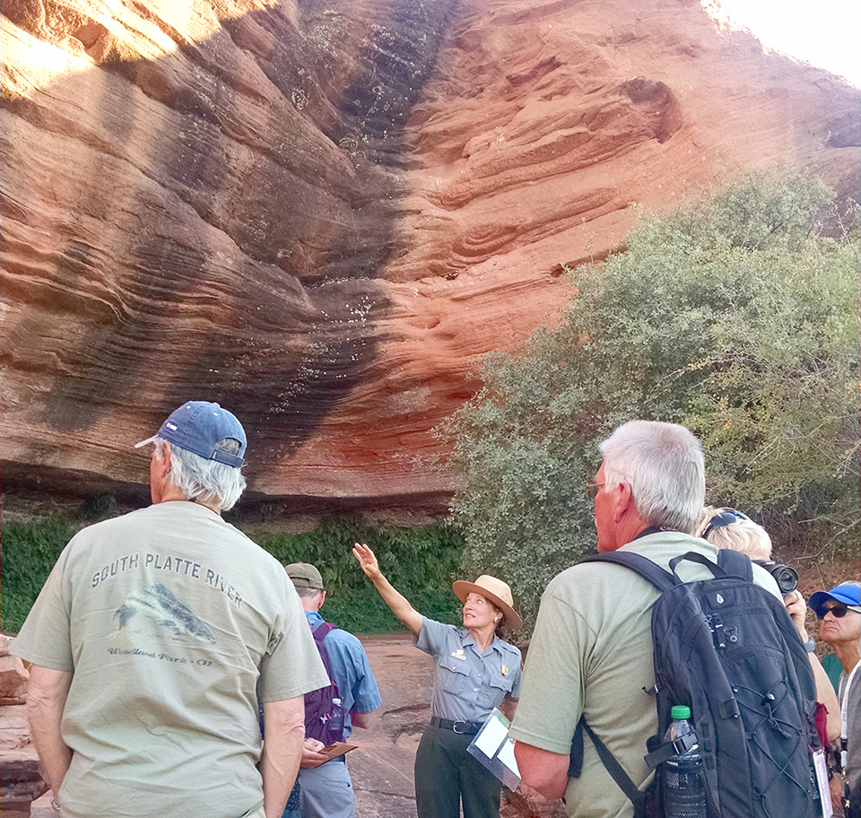 A ranger points to scenery in front of a crowd. A ranger points to scenery in front of a crowd.