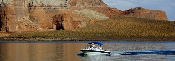 A boat glides across the still water with a sandstone cliff in the background. A boat glides across the still water with a sandstone cliff in the background.
