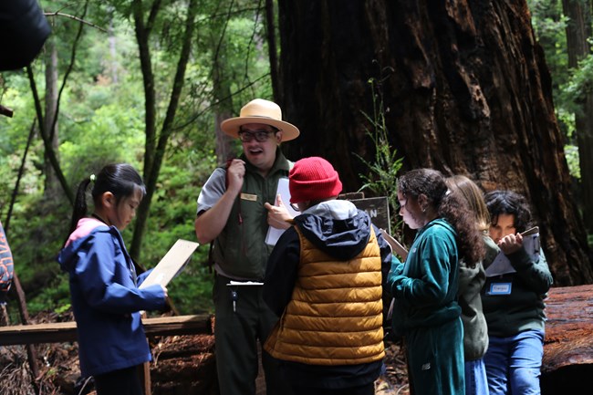 A ranger leads a lesson to a small group of students.