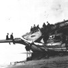 men assembled around a shipwreck lying on its side on a beach